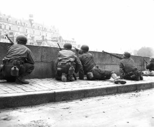 Cinq soldats américains s'abritant derrière le parapet du quai , en face du palais de justice, le 7 août 1944.