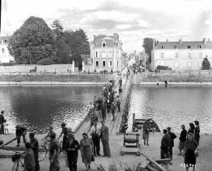 Civils, à pied ou à bicyclette, franchissant la Mayenne le 18 août 1944 sur un pont de bois construit par l'armée américaine dans le prolongement de la rue Crossardière.