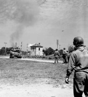 Soldats et tank américains près d'un passage à niveau lors d'une attaque aérienne à Saint-Aignan-de-Couptrain le 13 août 1944.